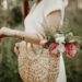 A Woman Carrying Woven Hand Bag with Colorful Flowers in it