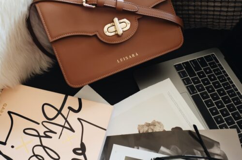 brown leather handbag beside macbook pro